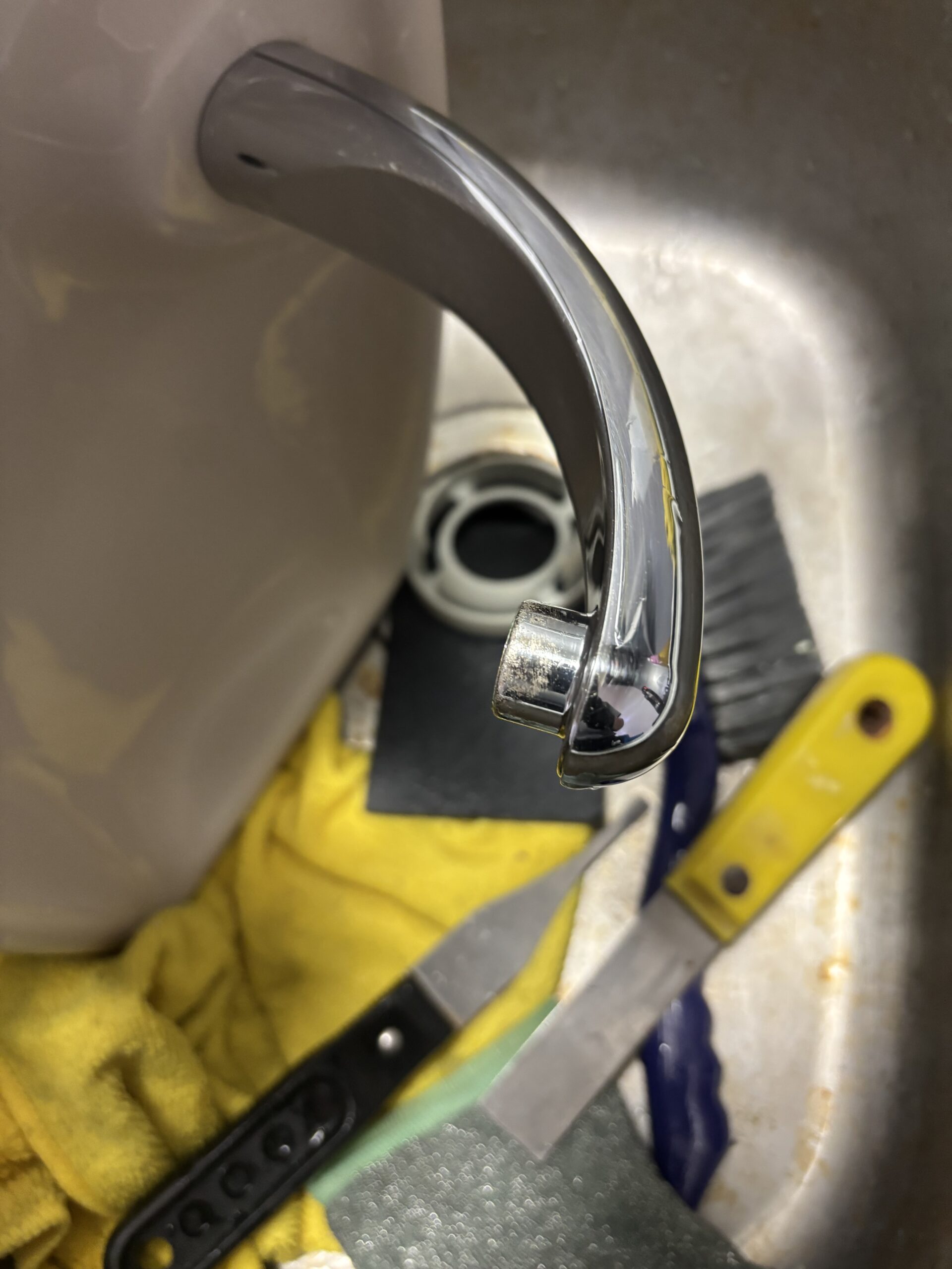 清掃後のトイレタンクの手洗い金具。反対側から撮影した吐水口と金具の表面