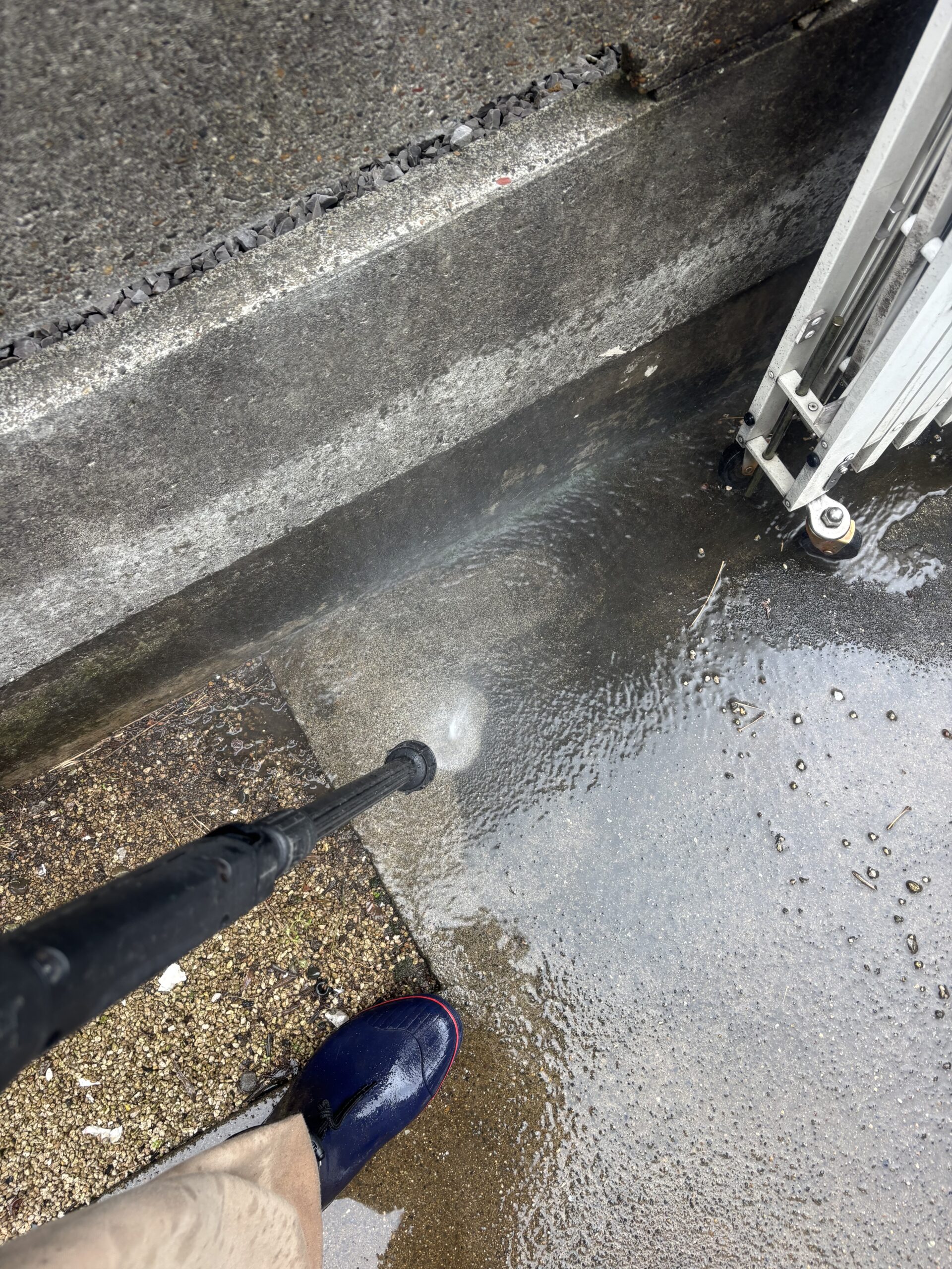 駐車スペースの端に高圧の水を当て、コンクリートの汚れを洗浄している様子