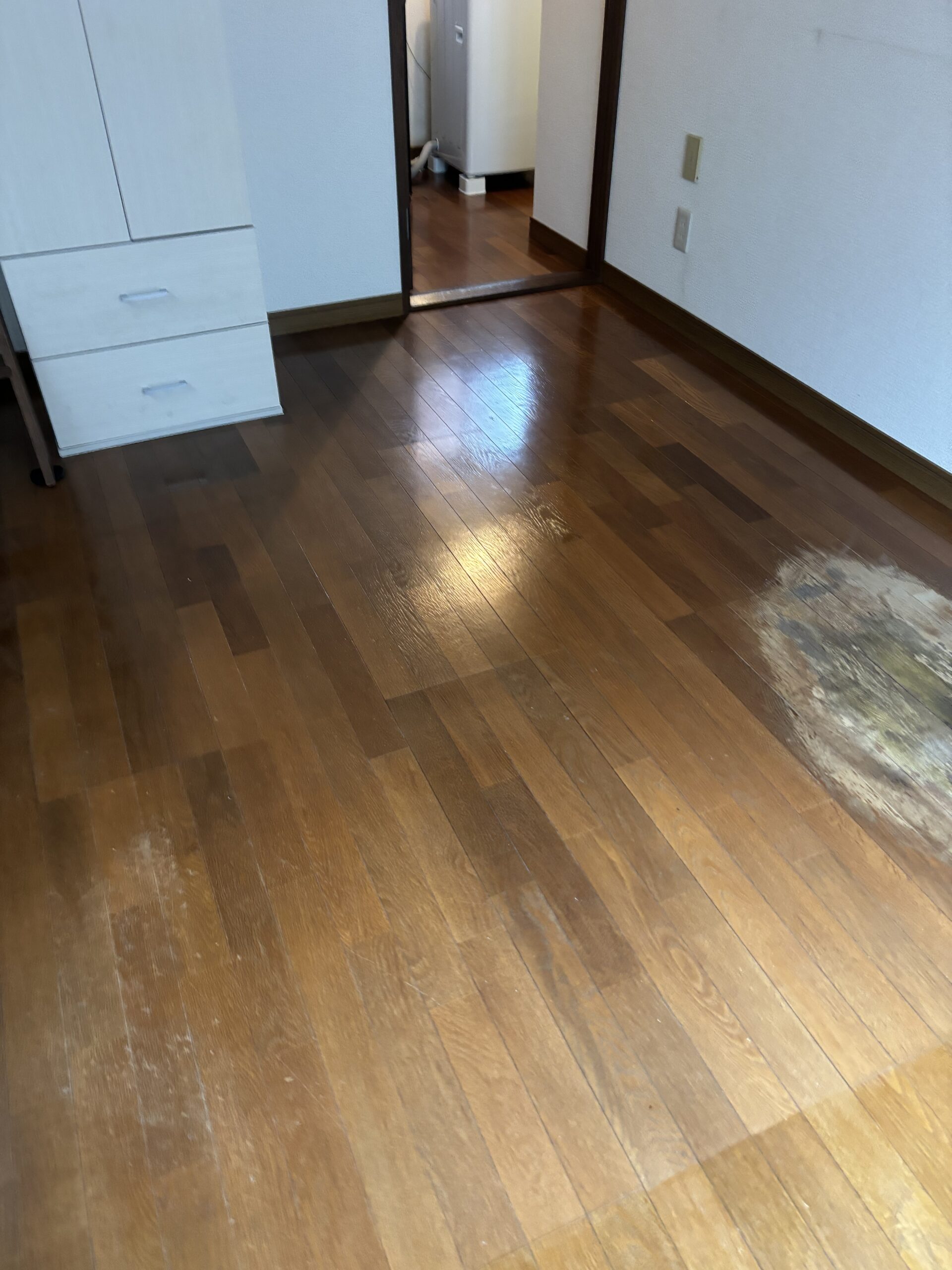 施工前の入口側のフローリング。白っぽく見える部分や染みがある床