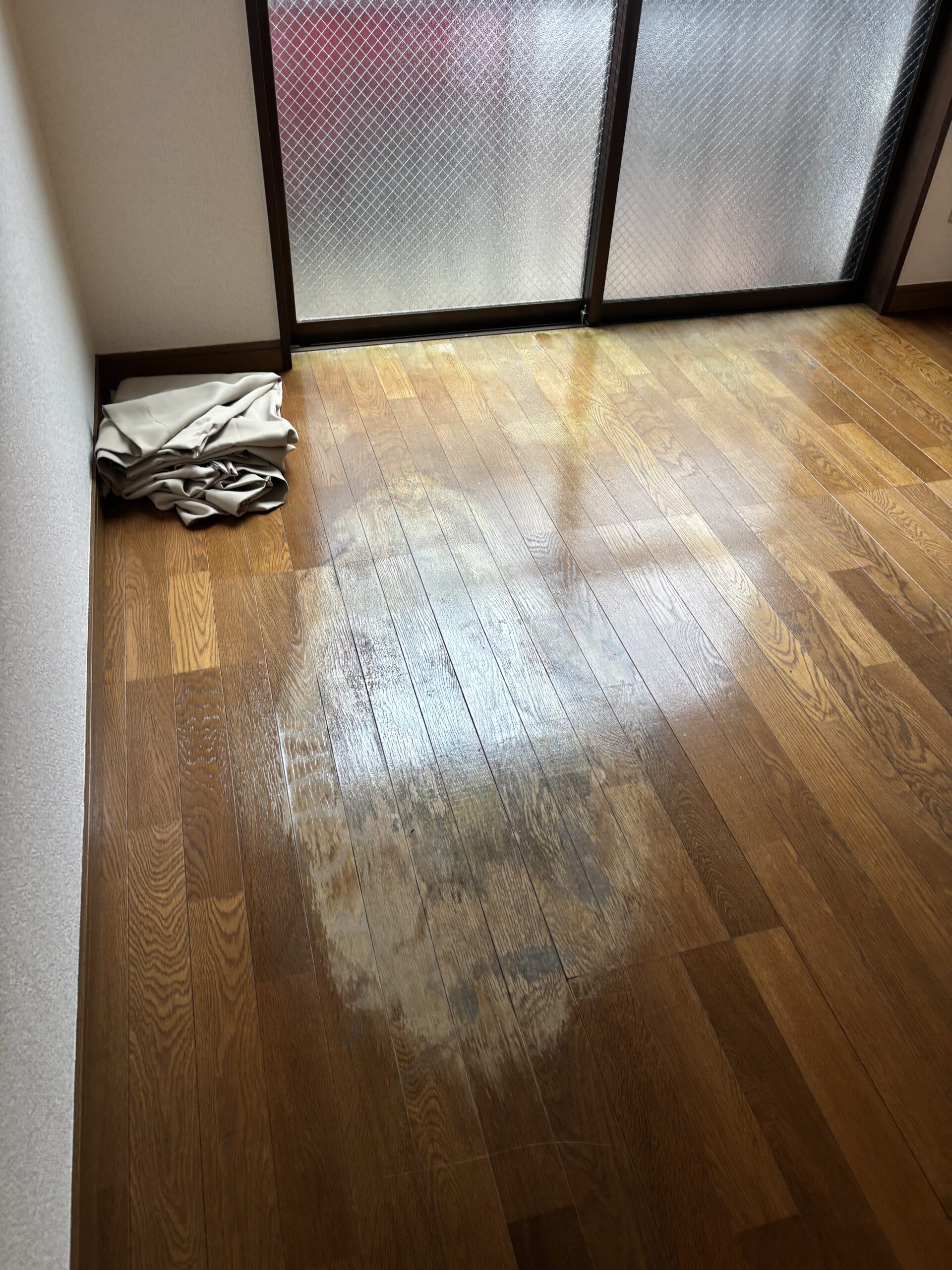 施工前の窓側のフローリング。床に染みや色むらが見られる