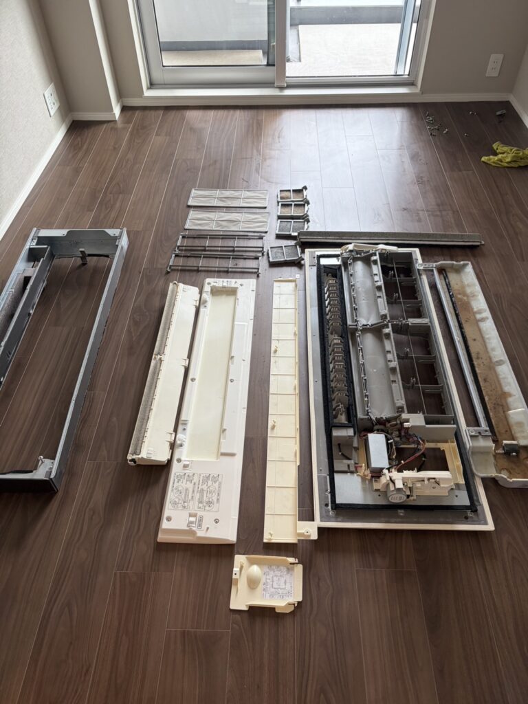 洗浄前の天井埋め込みエアコンから取り外したパネルやフィルターなどの部品。汚れが残っている状態